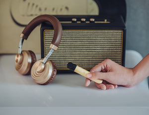 RELX Infinity Gold dipegang di depan sebuah radio dan headphone gold