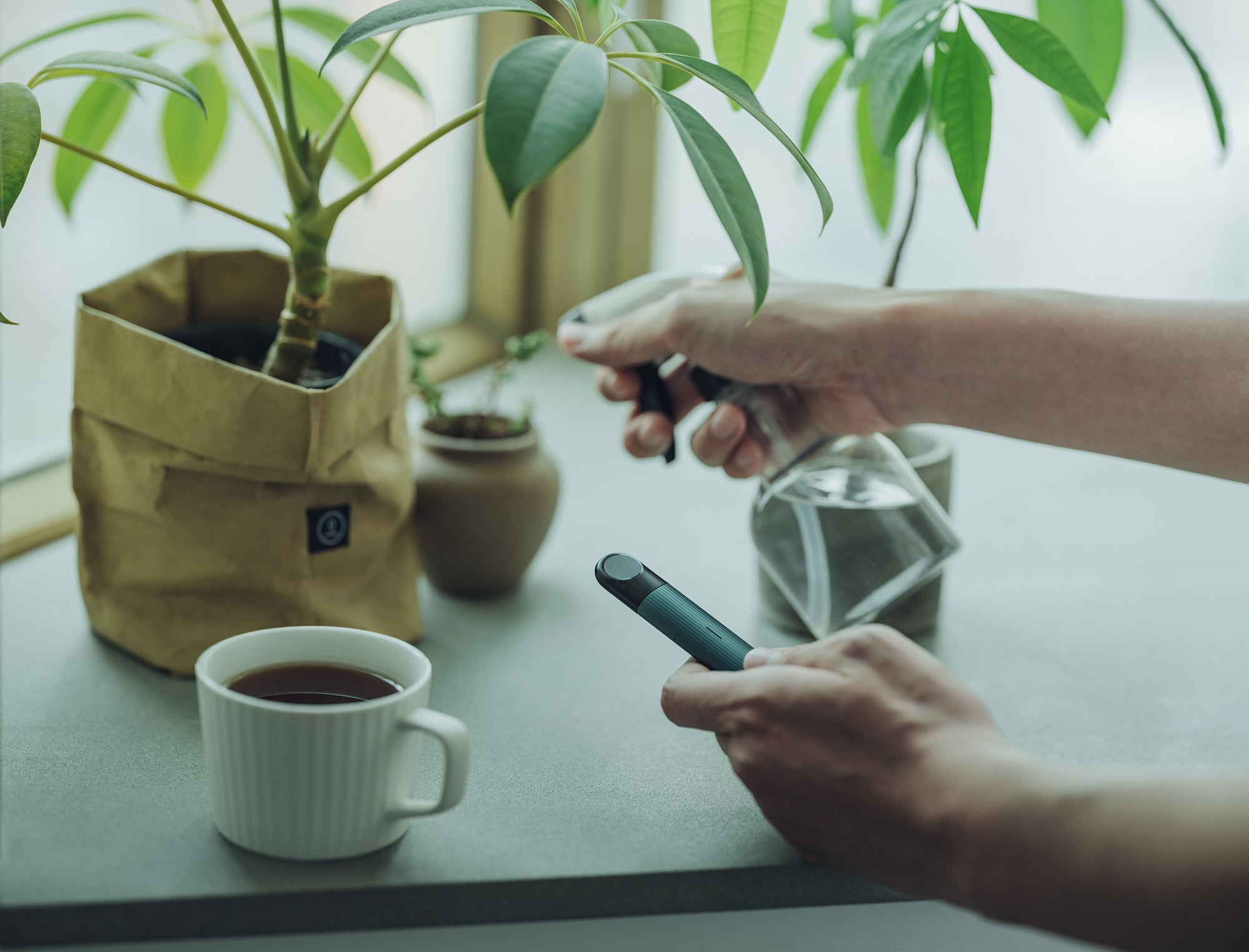 RELX Infinity di tangan seseorang dengan secangkir kopi di sebelahnya