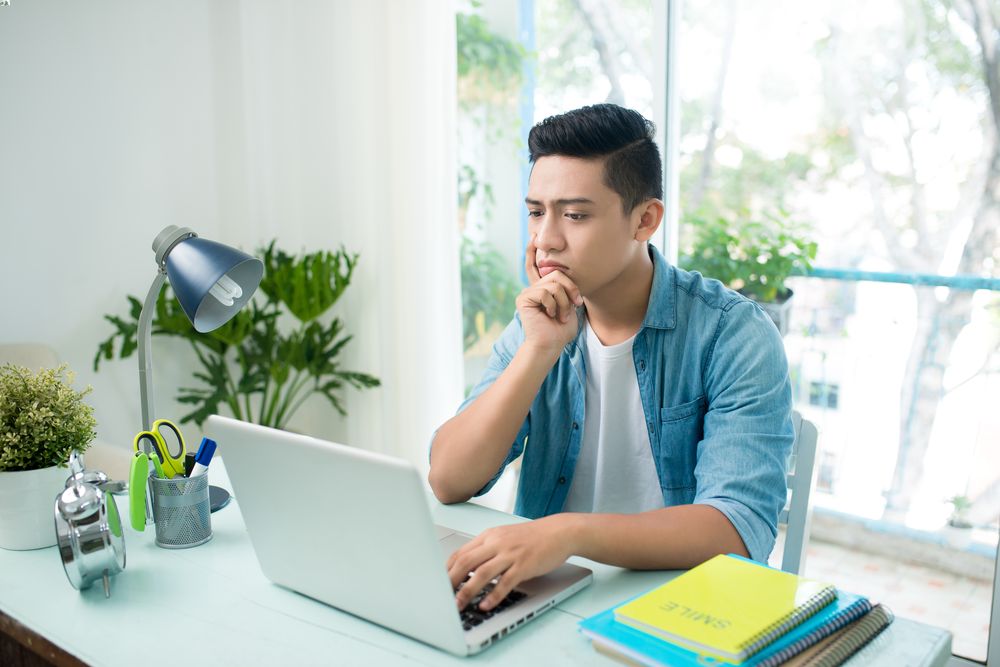 Seorang pria dengan ekspresi serius sedang menatap layar laptop