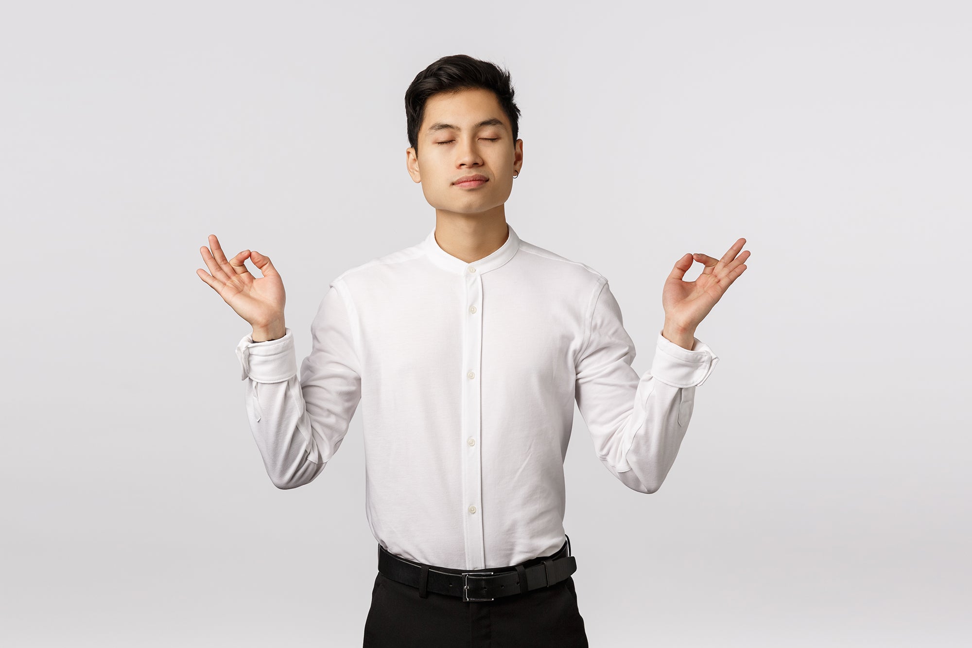 Seorang pria berbaju putih memasang postur meditasi