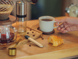 RELX Infinity di atas meja kayu dengan cangkir kopi dan sepotong roti