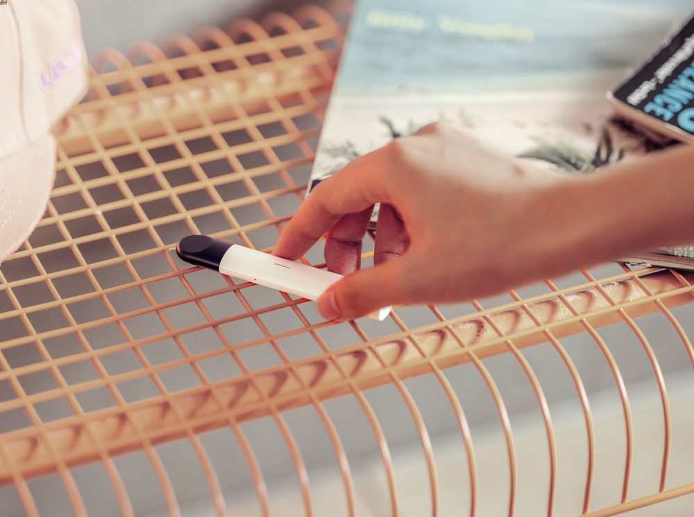 Seseorang sedang mengambil RELX Essential putih dengan tangan kanannya